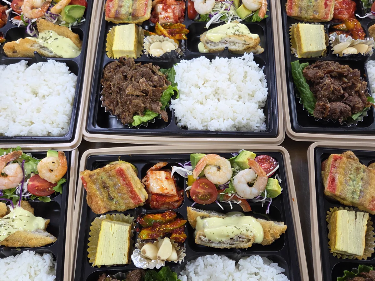 밥과 고기 메인, 달걀말이, 새우 샐러드와 반찬을 같은 구성으로 여러 개 준비한 실제 단체도시락